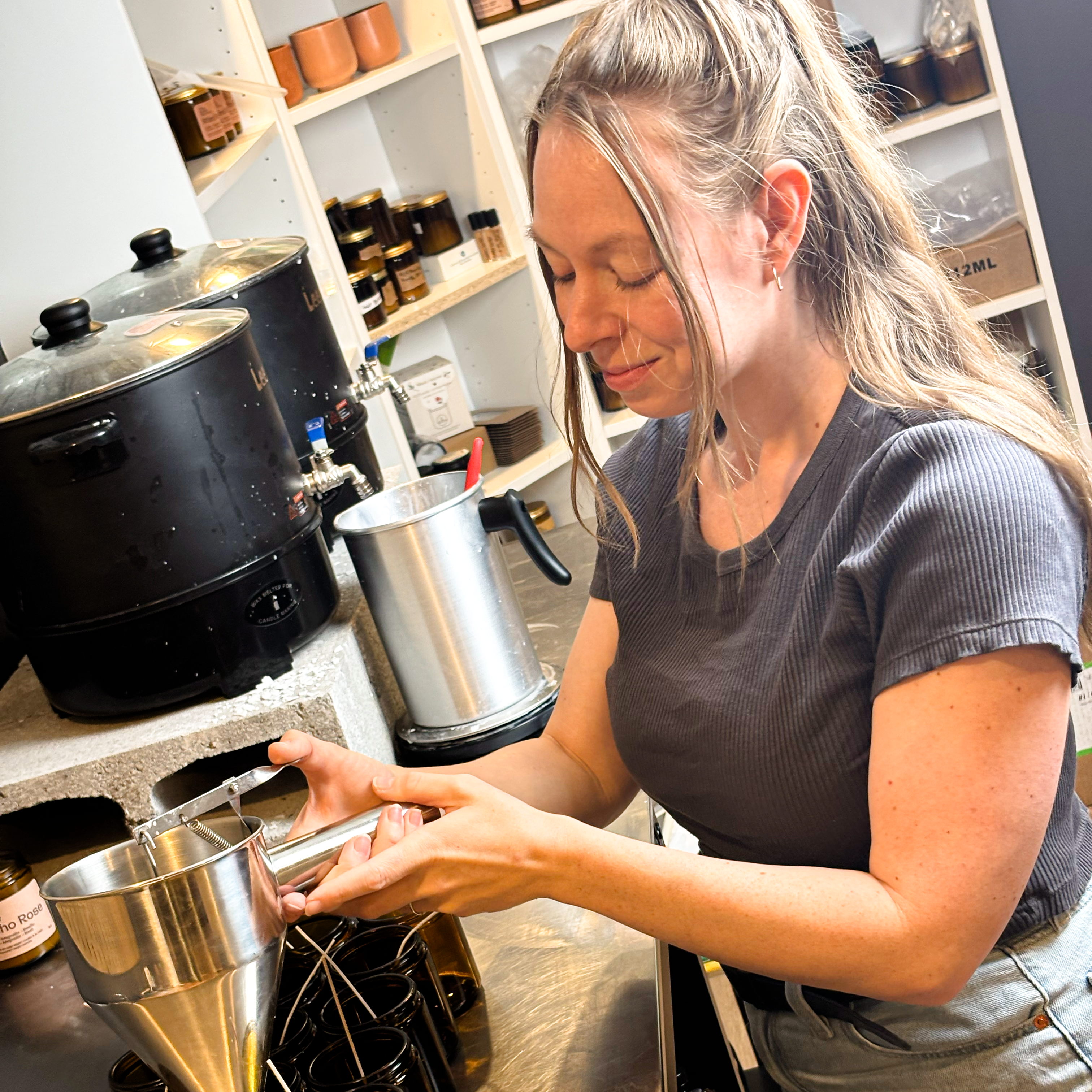 Artisane coulant des bougies à la main avec équipement professionnel dans atelier
