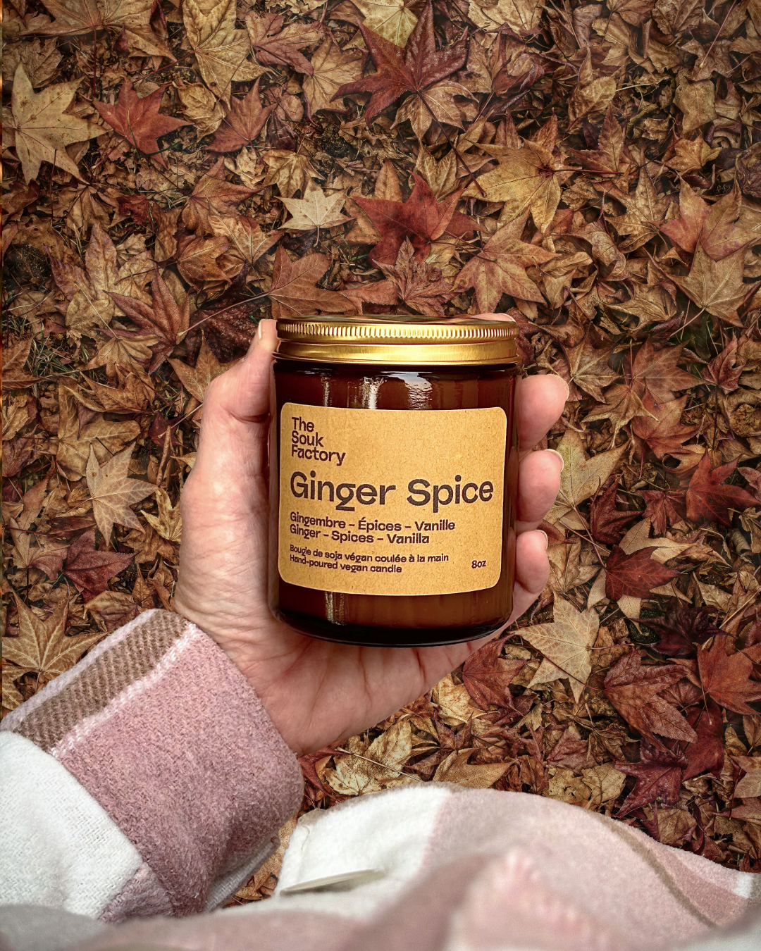 Bougie Ginger Spice dans une main avec feuilles d'automnes